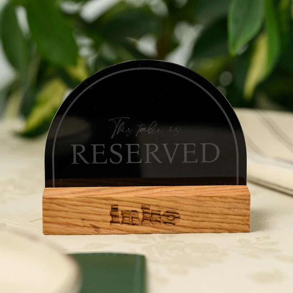 Front view of a semicircle black acrylic 'Reserved' sign on a wooden block base