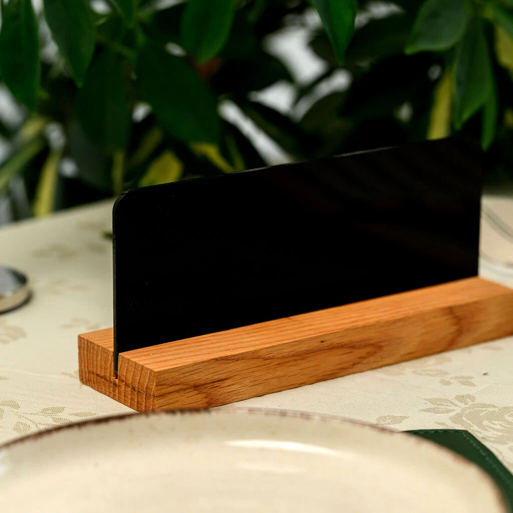Rear view of a modern table sign showing the sleek black acrylic plate securely fitted into a solid oak wood base on a restaurant table