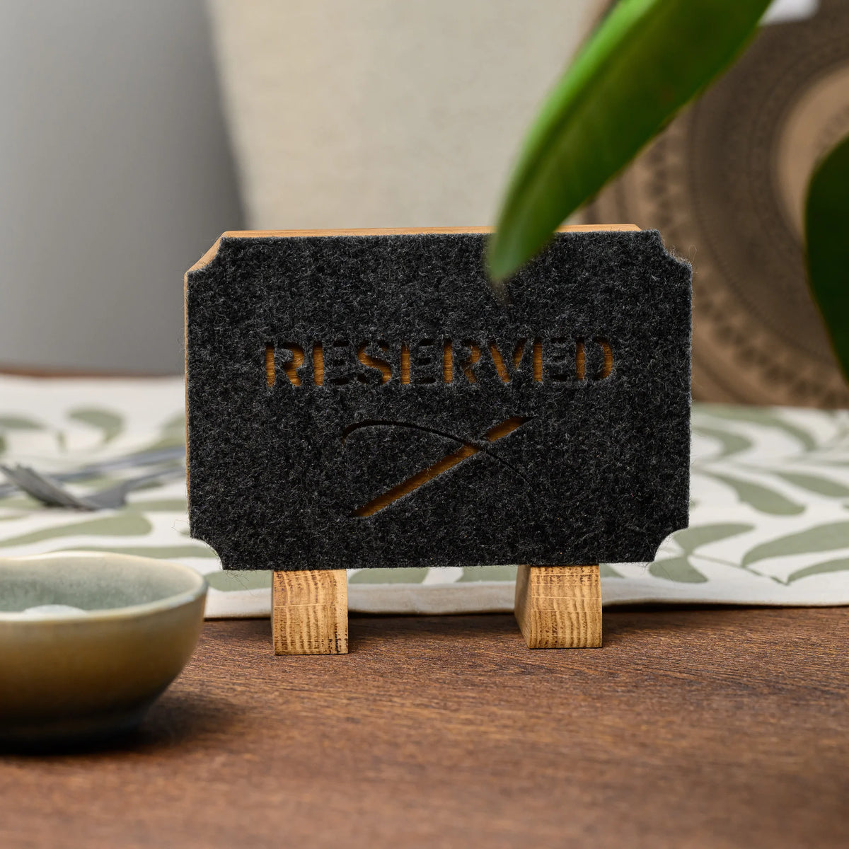 Дубова табличка «Reserved» з прорізаним фетром, макрознімок торця: скошений кут дубової основи, край сірого фетру та дубова опора