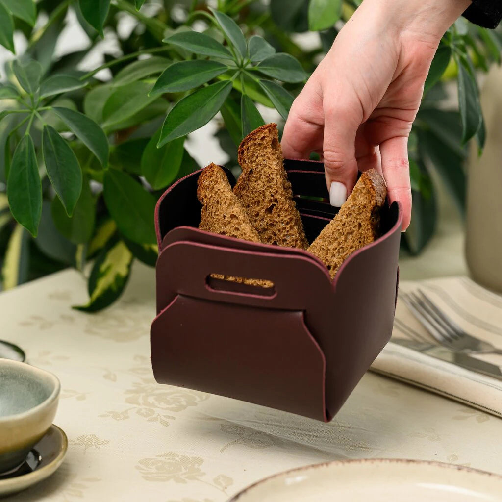 Artisan dark bread served in a luxury wine-colored leather holder, showcasing a minimalist and elegant table setting
