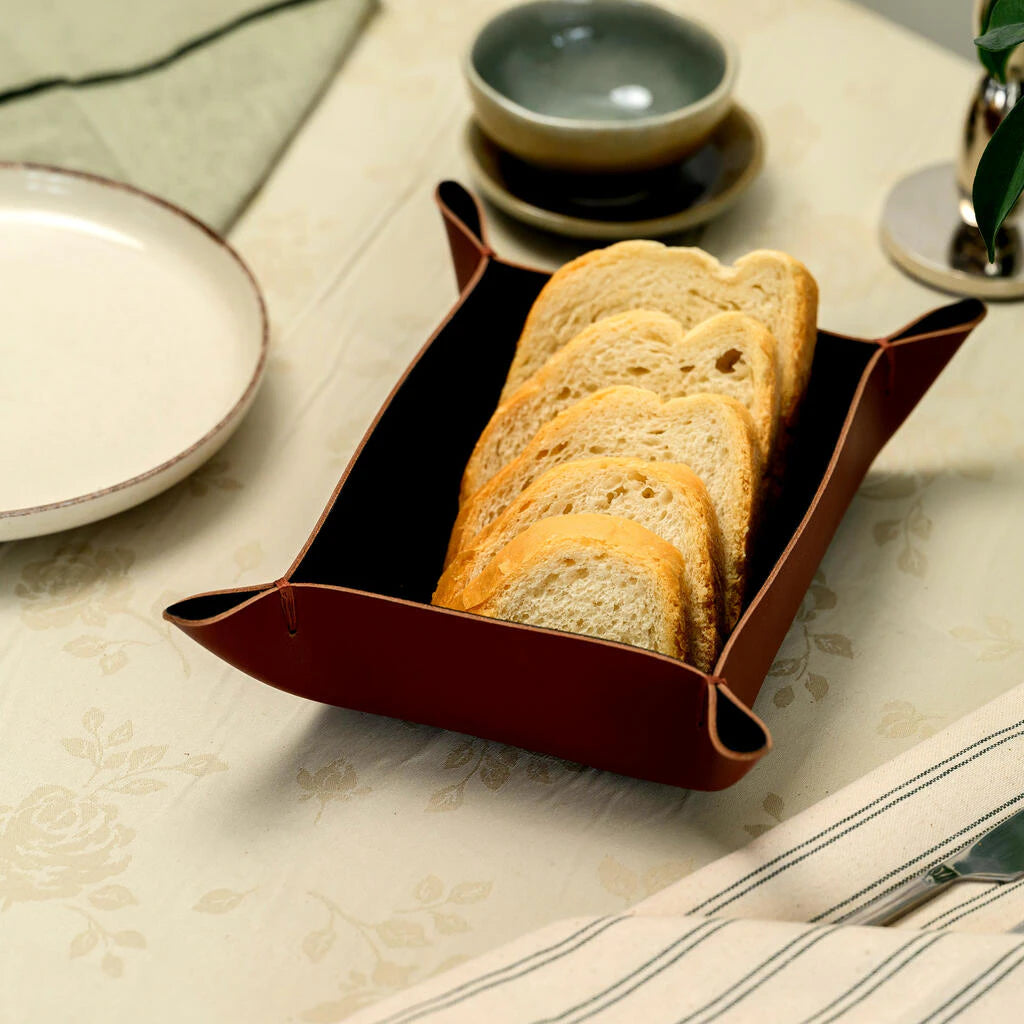 Premium leather tissue box cover in a rich tan color. This artisan table accessory is shown in a professional dining environment, highlighting its sophisticated rustic look and practical design for high-end hospitality branding