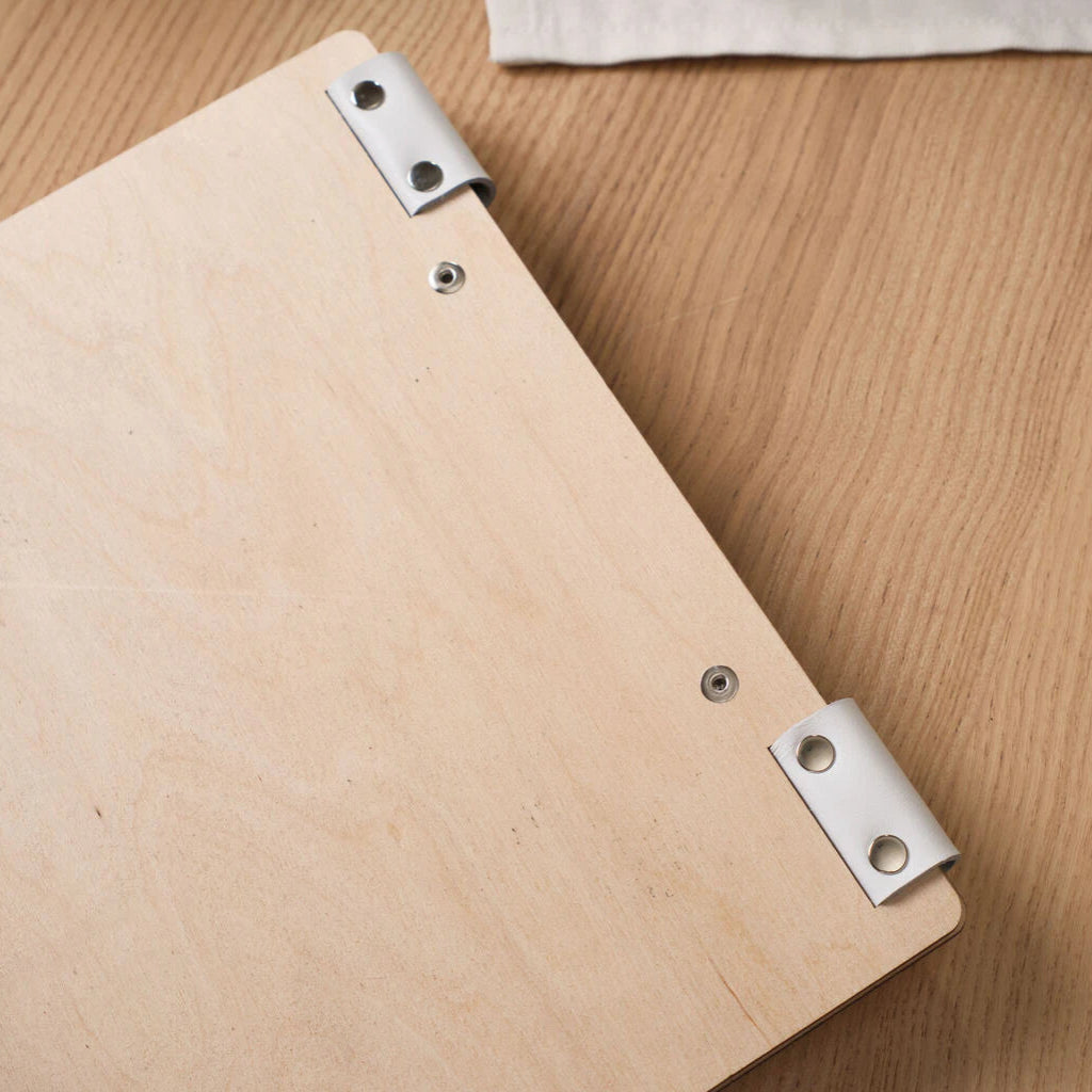 Close-up of the back of a light wood menu folder highlighting clean rivets and smooth wood texture.