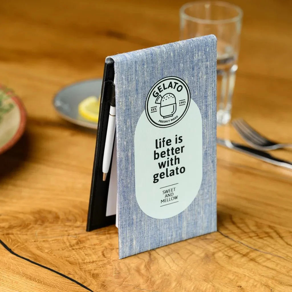 A close-up of a fabric-bound notebook with a firm hardcover, perfectly suited for waiters. The detailed texture of the fabric cover adds a touch of professionalism, and the rigid hardback ensures a stable writing surface for taking orders quickly and efficiently.