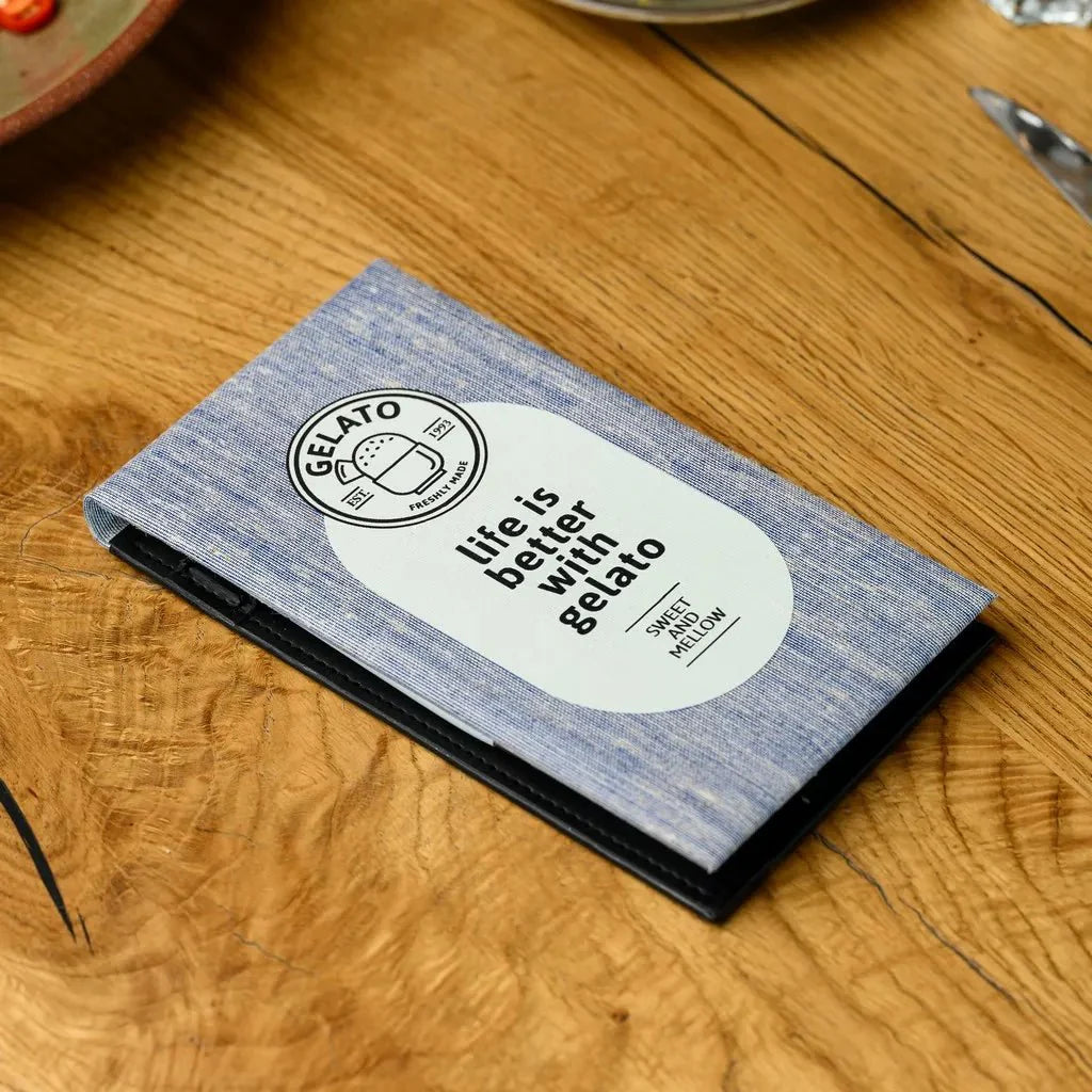 Picture of a hardcover notebook wrapped in a refined fabric material, intended for use by restaurant waiters. The notebook's robust design, including a stiff hardback, allows for comfortable and precise note-taking during hectic service hours.