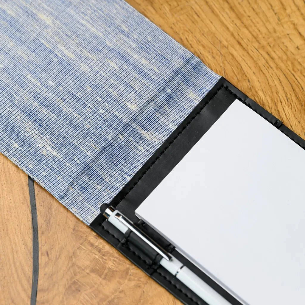 Detailed view of a waiter's notepad with a fabric exterior and a solid hardcover. This notebook is designed to offer a blend of sophistication and durability, ensuring waiters can maintain organized and legible records of customer orders.