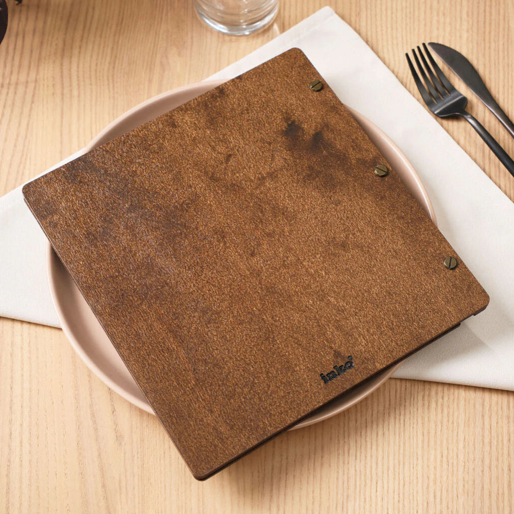 Close-up of a hand flipping a printed menu page inside a premium wooden binder.