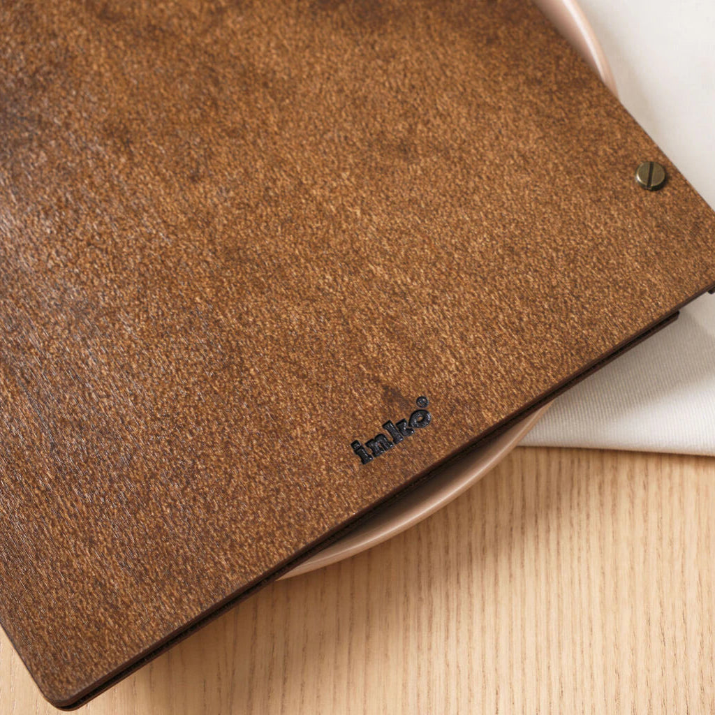 Rear view of a menu folder featuring a small engraved "inko" brand logo and leather hinge.