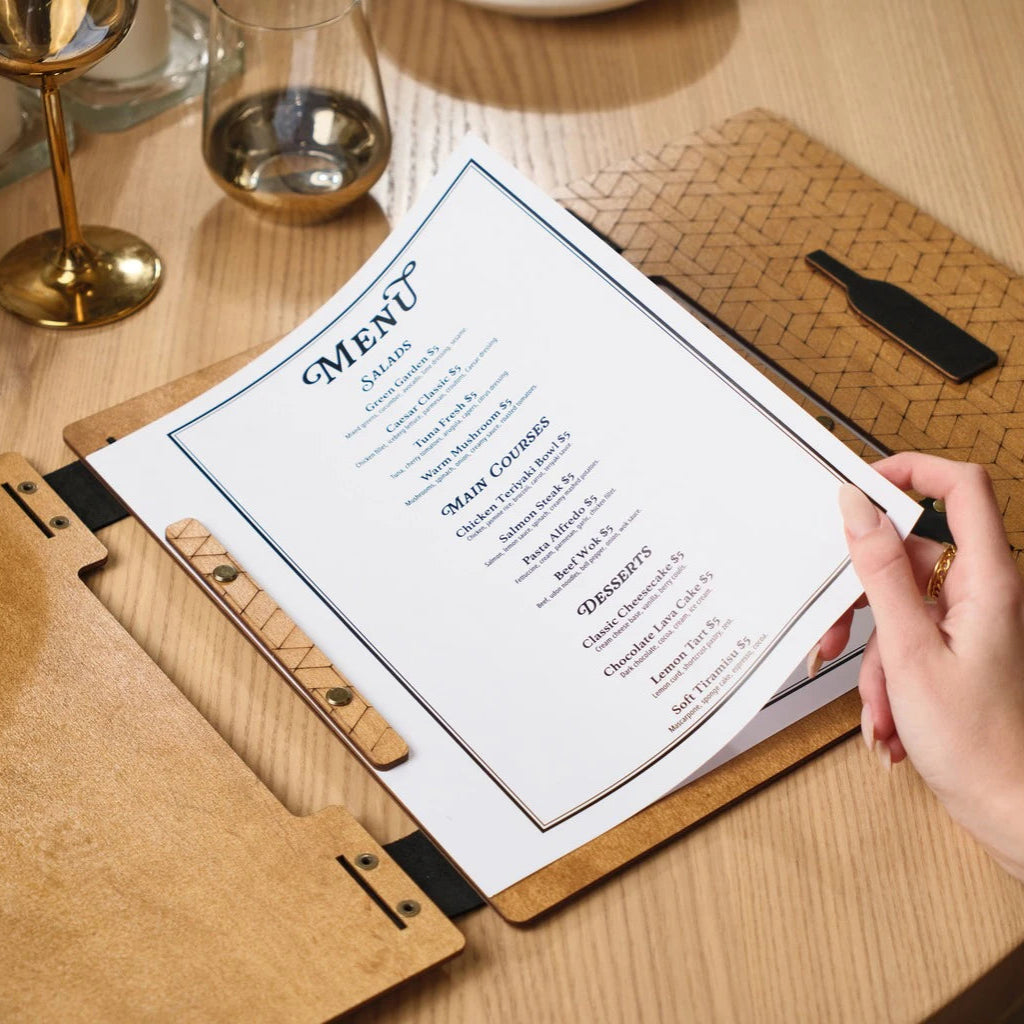 Close-up of a menu being held, focusing on the textured wooden strip with engraving that secures the paper in place
