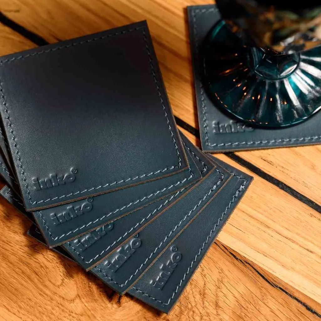 Комплект квадратних підставок зі шкіри Capri на дерев’яному столі