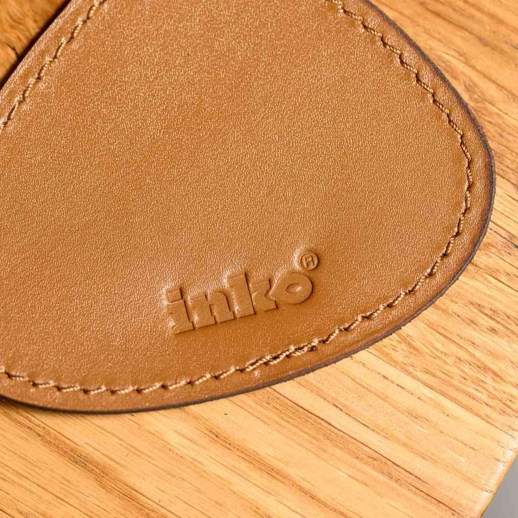 Комплект підставок у формі каплі зі шкіри Capri на дерев’яному столі