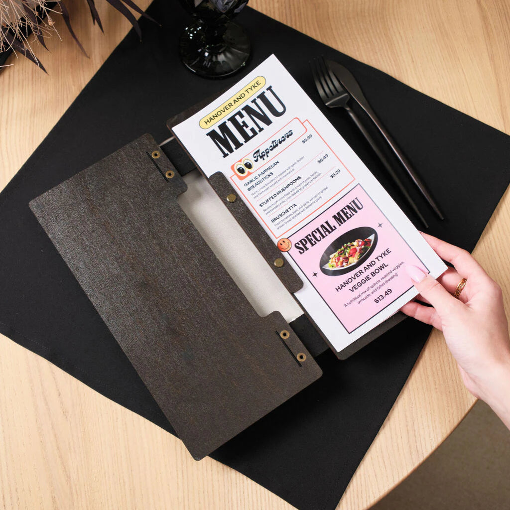 A black leather strap, secured with two antique brass rivets, wraps around the edge of the folder, providing both a structural and decorative element.