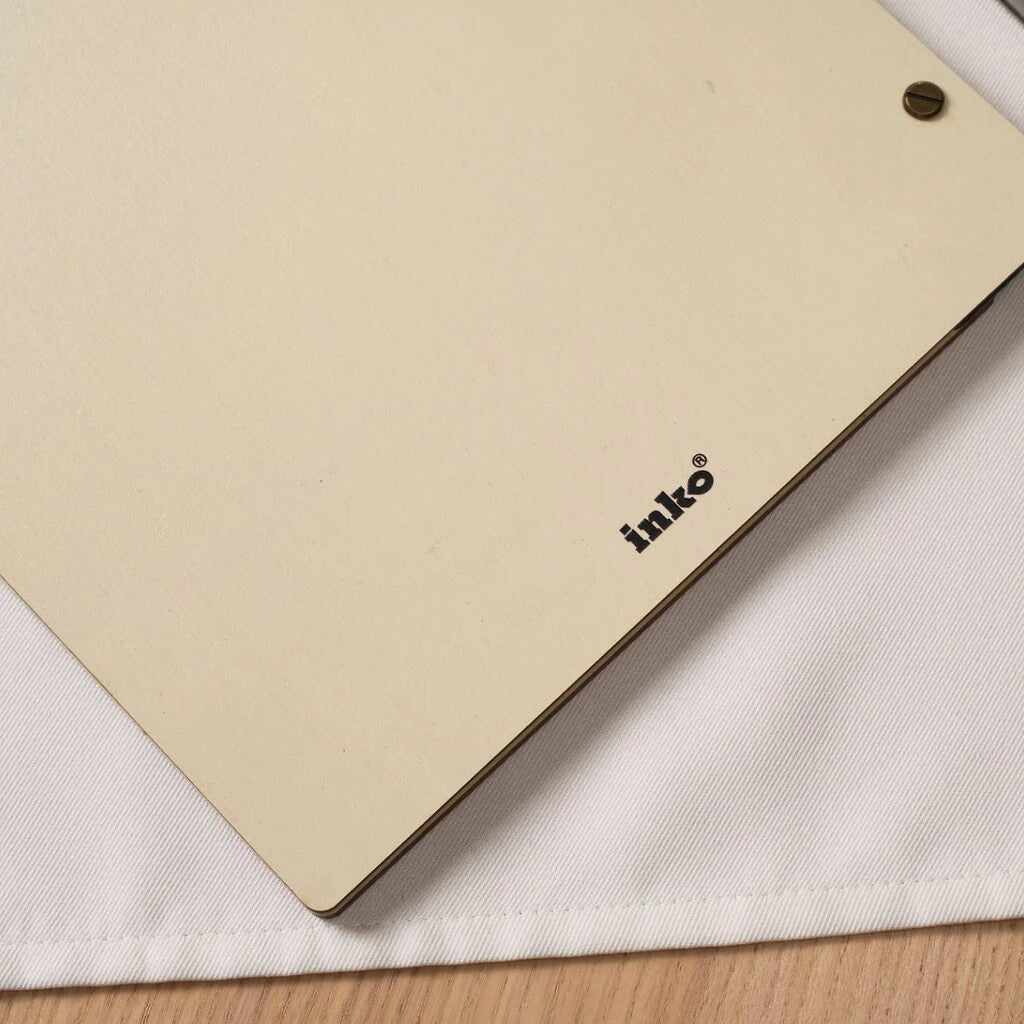Close-up of Inko wooden menu cover corner with brass screw on white linen napkin