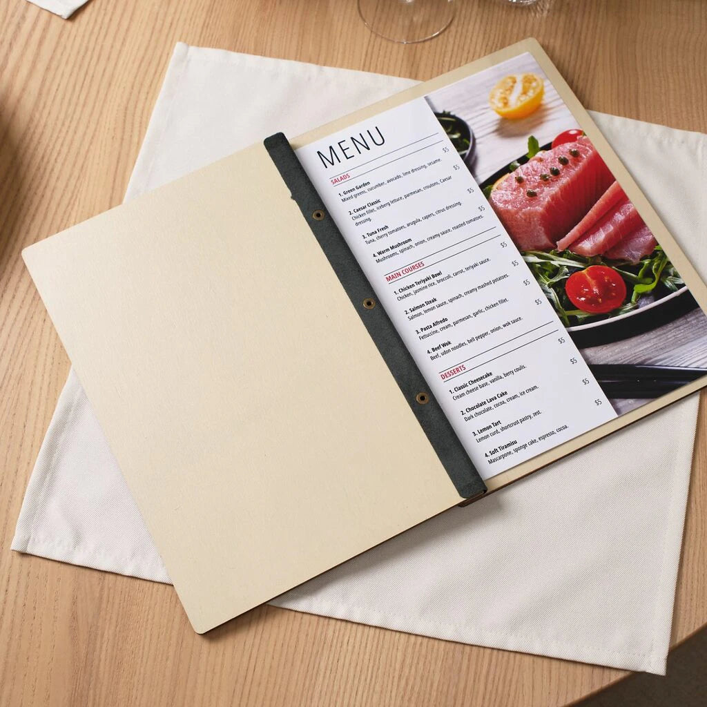 Open wooden menu cover with printed food menu and salmon photo on white linen napkin on wooden table