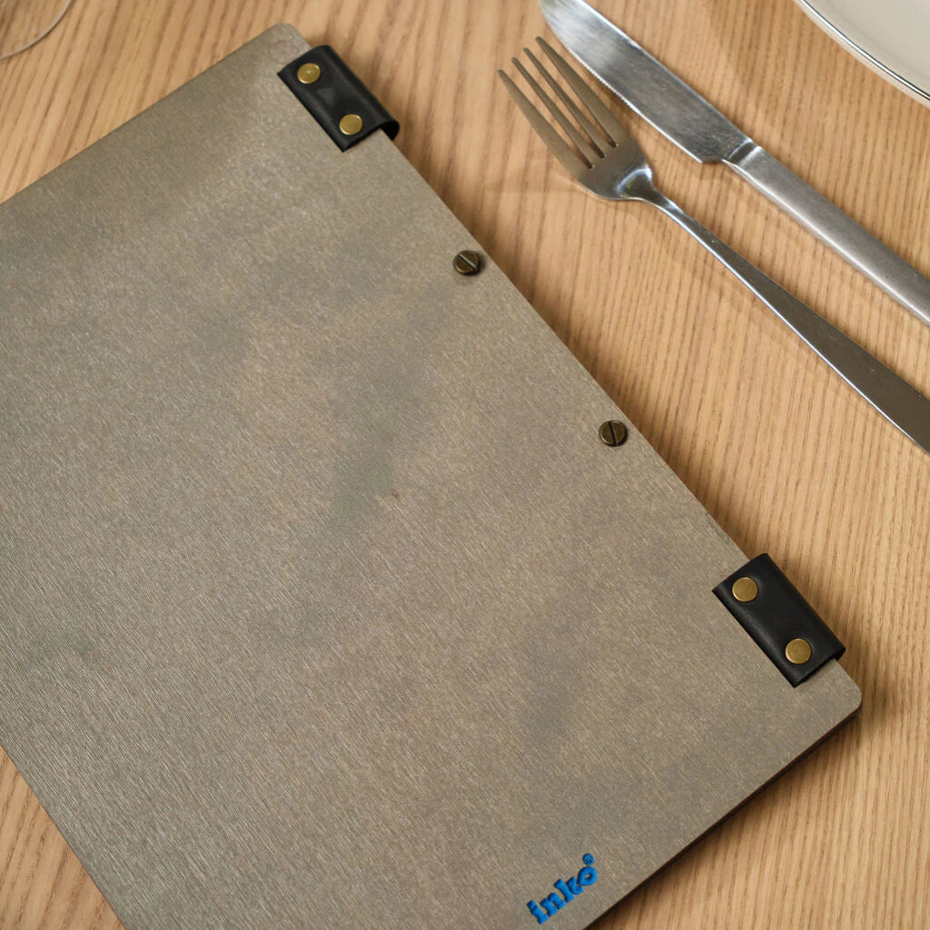 A top-down view of the back of a grey wooden menu folder, highlighting the natural wood texture, black leather spine accents, and a small blue "inko" brand logo at the bottom.