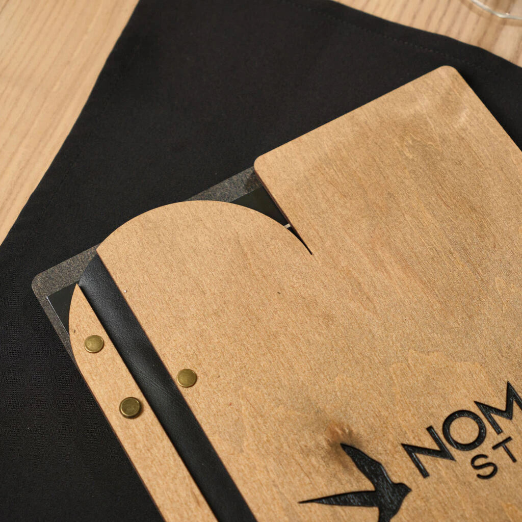 Top view of the custom-shaped edge of a wooden menu folder made from natural oak with a contrasting black interior