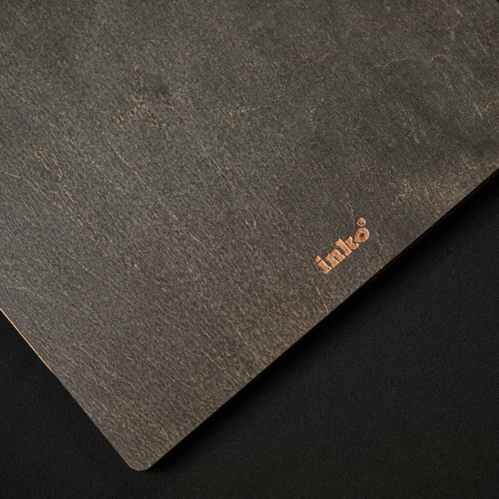 Macro detail of the dark wood texture on the back of the folder, featuring a subtle gold-embossed "inko" logo