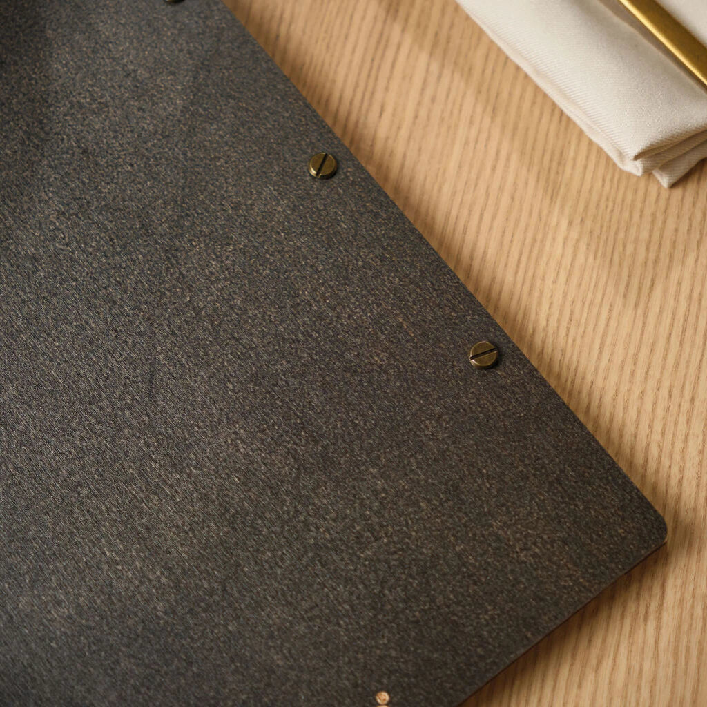 Detailed shot of the back of a custom restaurant menu board, showing the secure antique brass screw fasteners against the dark textured wooden surface