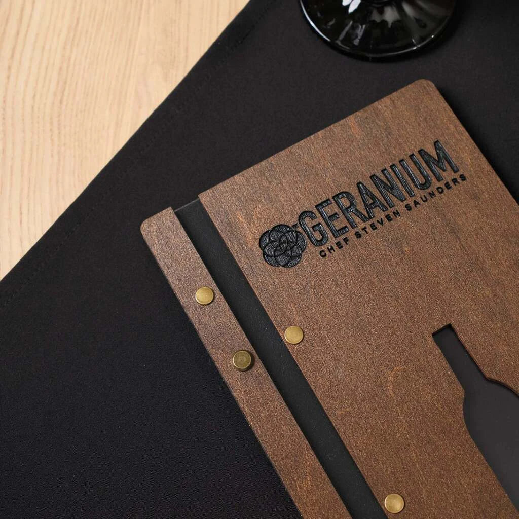 A macro shot of the top left corner, focusing on the precision of the engraved branding and the warm, natural grain of the walnut wood.