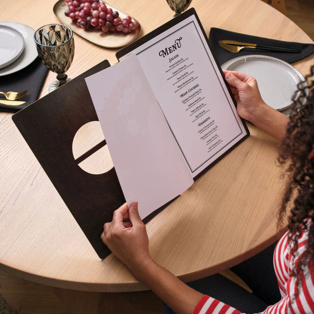 The panels are joined by a flexible black binding. Internal pages are secured by a matching wooden strip held in place with brass-colored rivets.