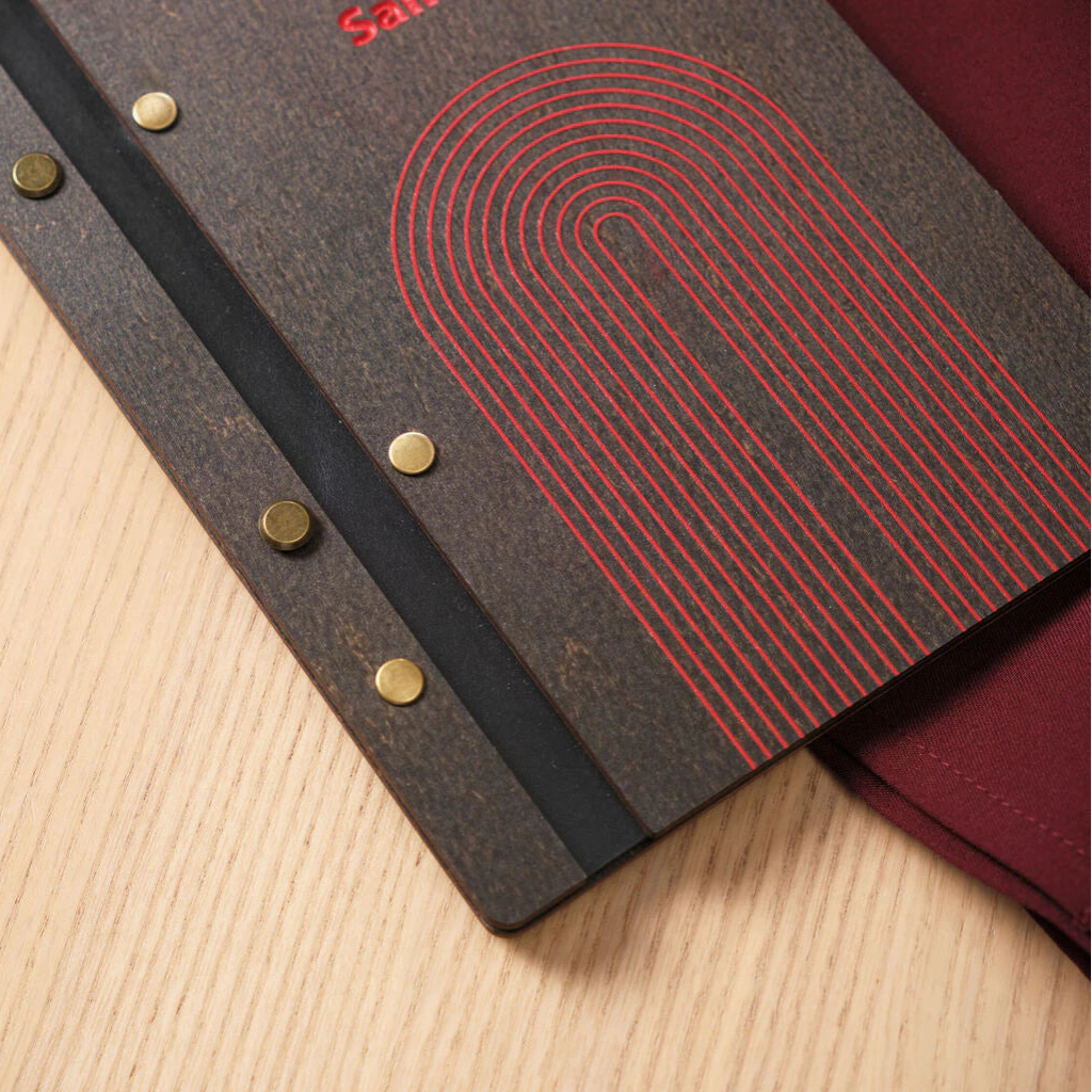 A close-up focusing on the bottom section of the menu, displaying the fine lines of the red engraved arch pattern and the textured surface of the dark wood.