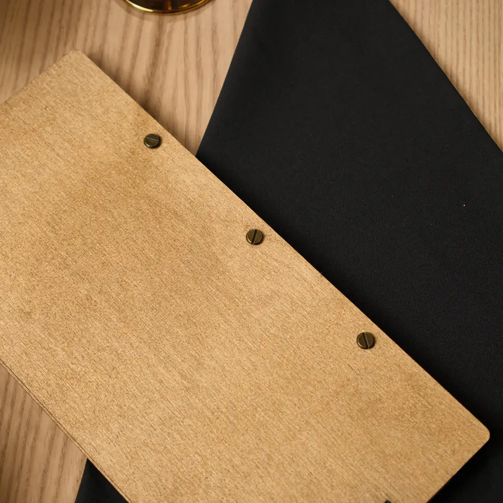 A close-up of the back cover of the oak-colored wooden folder, showing three dark, slotted brass screws used for the binding.
