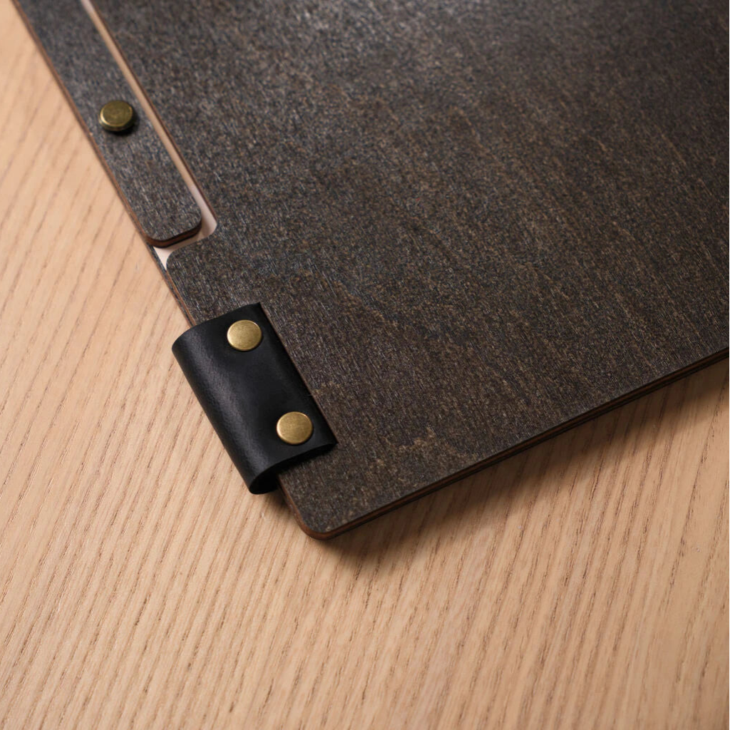 Close-up of the black leather hinge and the textured wood grain.