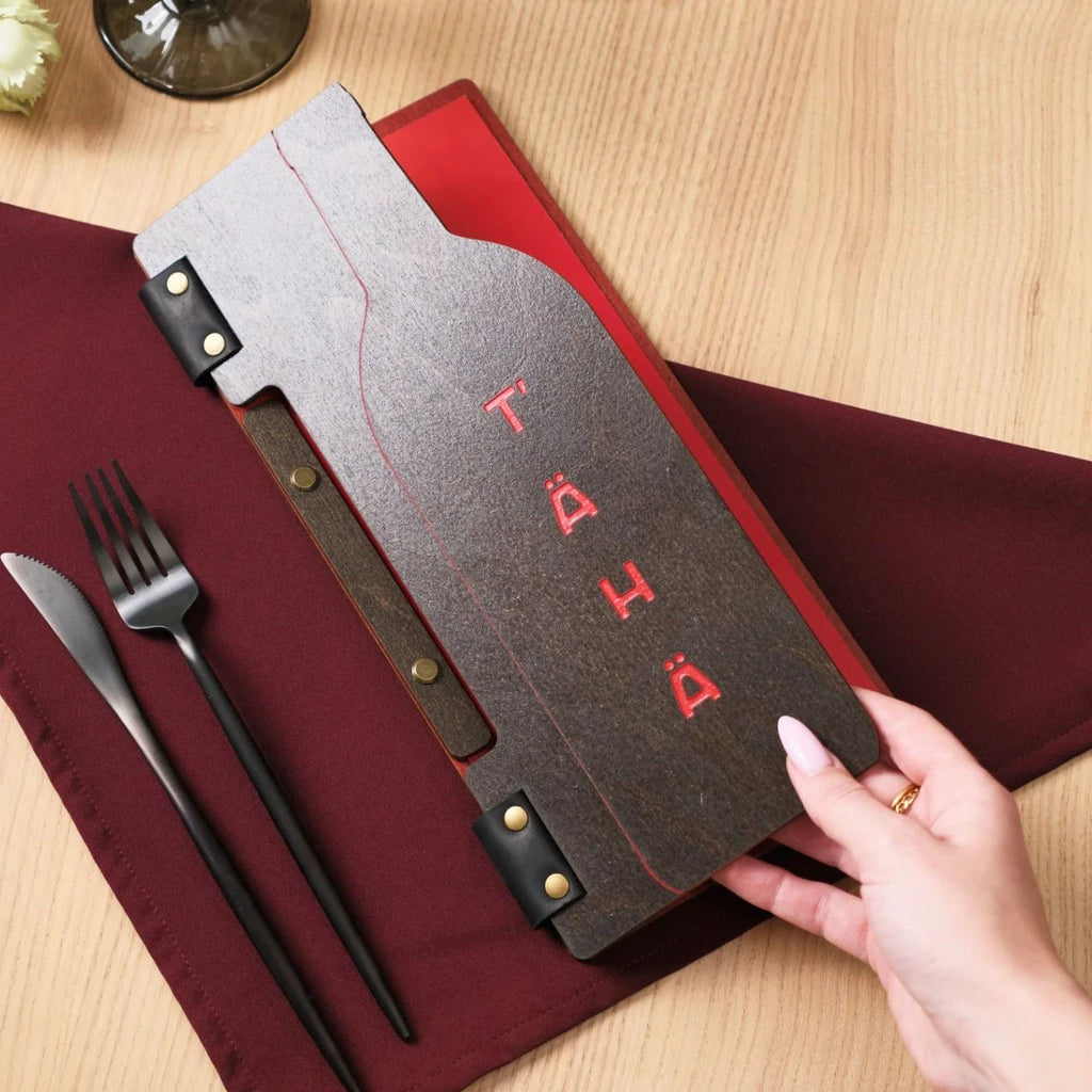 Custom wooden menu folder with a unique wine bottle cutout and vibrant red color engraving. This handcrafted menu cover features a dark wood finish, black leather accents, and secure bolt binding