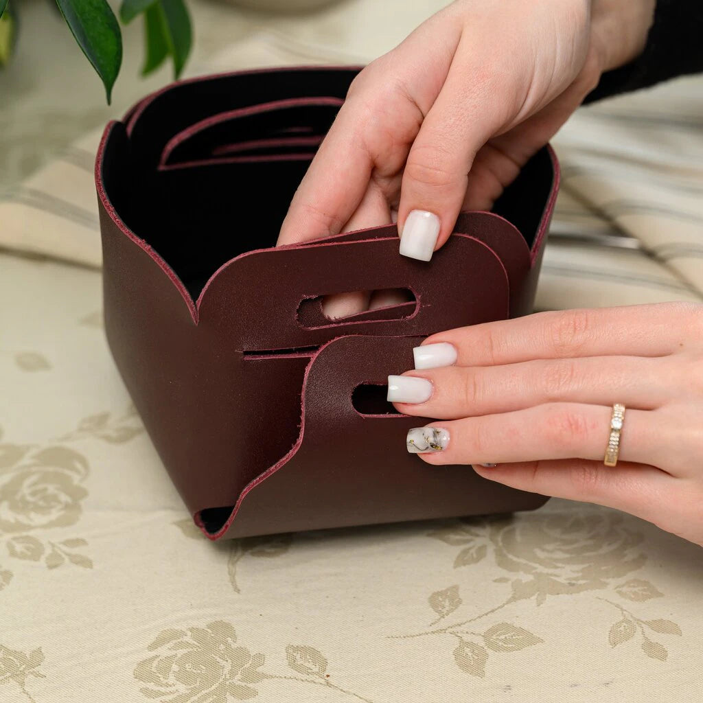 Step-by-step assembly of a no-stitch leather basket, highlighting the clever interlocking mechanism and the flexible yet durable nature of the burgundy leather material