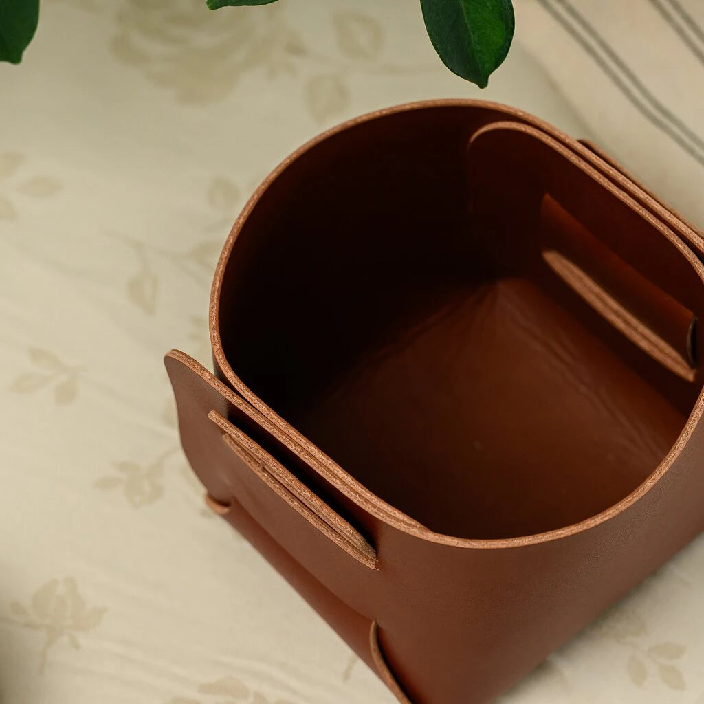 High-angle shot of a premium handcrafted leather valet tray or bread bin, showcasing the rich grain and seamless assembly of the material.