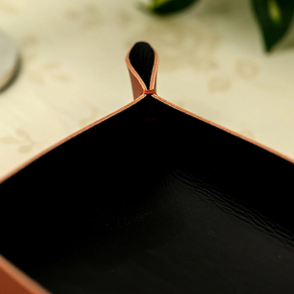 A close-up shot of a leather bread tray's folded corner, secured with reinforced stitching. The image emphasizes the rich tan color, matte finish, and professional craftsmanship, perfect for upscale hospitality table settings