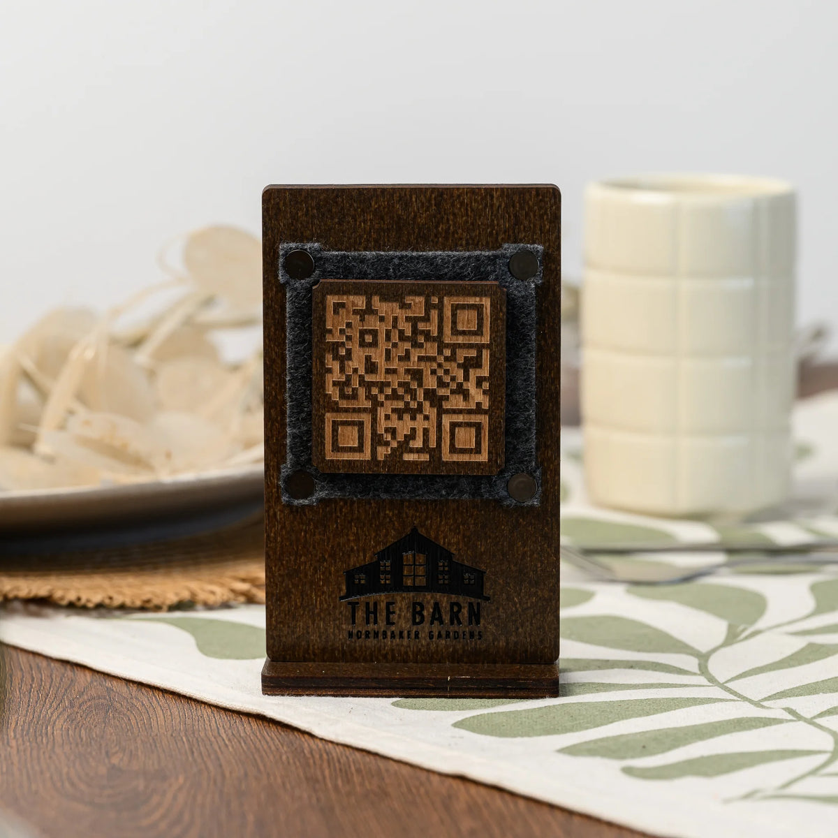 Двосторонній фанерний QR стенд з гравіюванням на столі, вигляд спереду: QR-код на фетровій вставці та логотип закладу поруч із чашкою