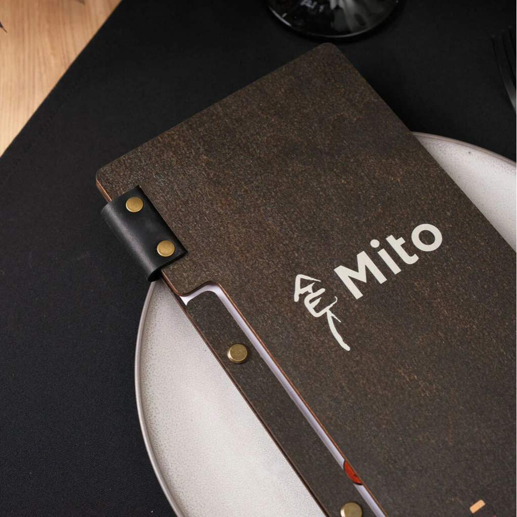 A detailed close-up of the front cover highlights the white UV-printed "Mito" logo and a black leather strap secured with antique brass rivets against the dark wenge wood grain.