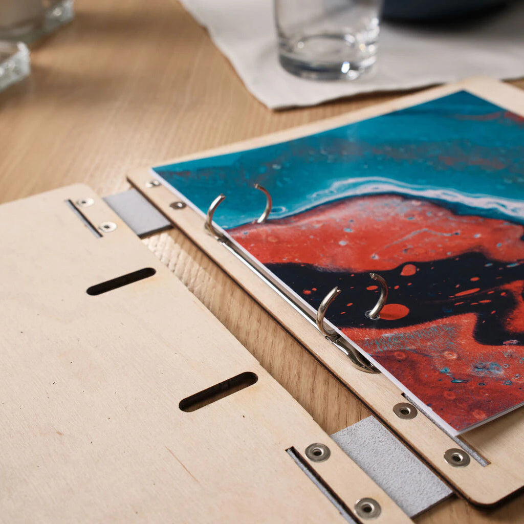 Detail of the durable chrome ring mechanism inside a light wood binder, designed for easy menu page updates.