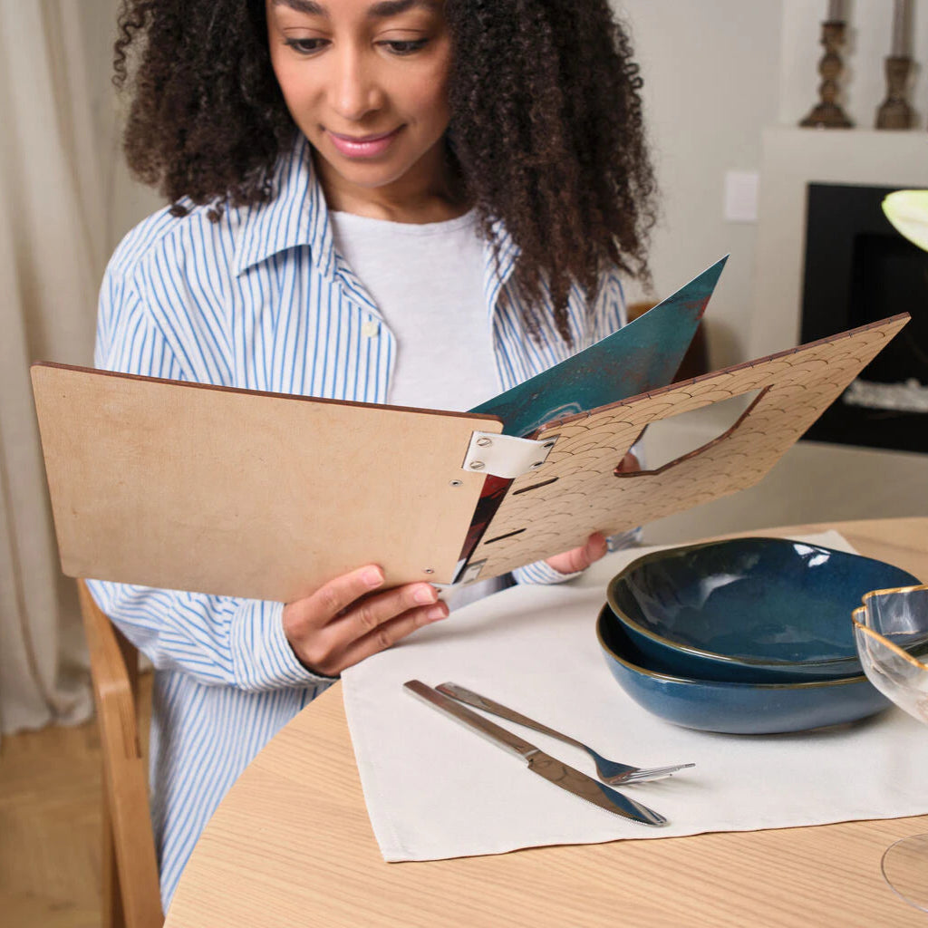 Rear view of a light wood menu cover highlighting the minimalist finish, metal rivets, and white leather binding straps.