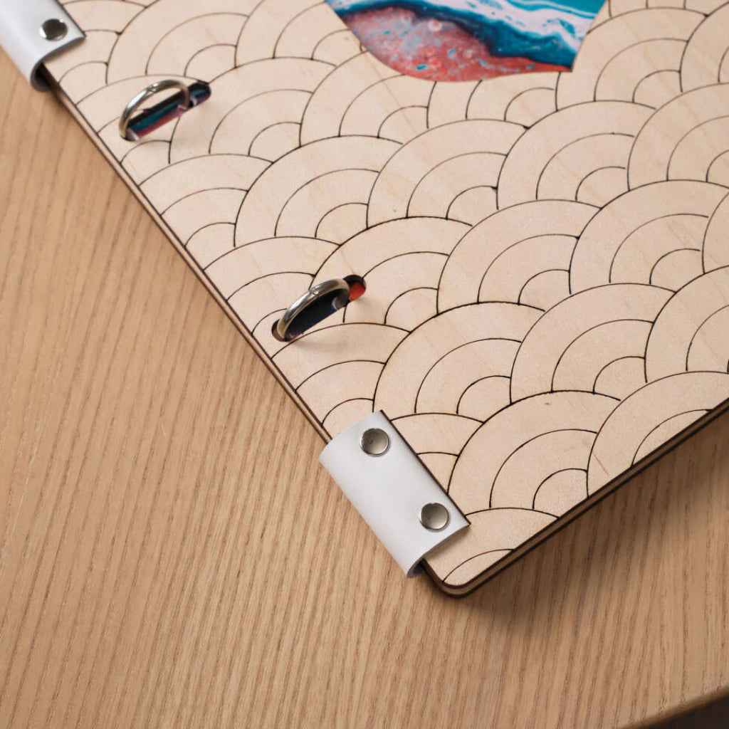 Angle view of a light wood menu cover edge, showing deep wave pattern and chrome binding details.
