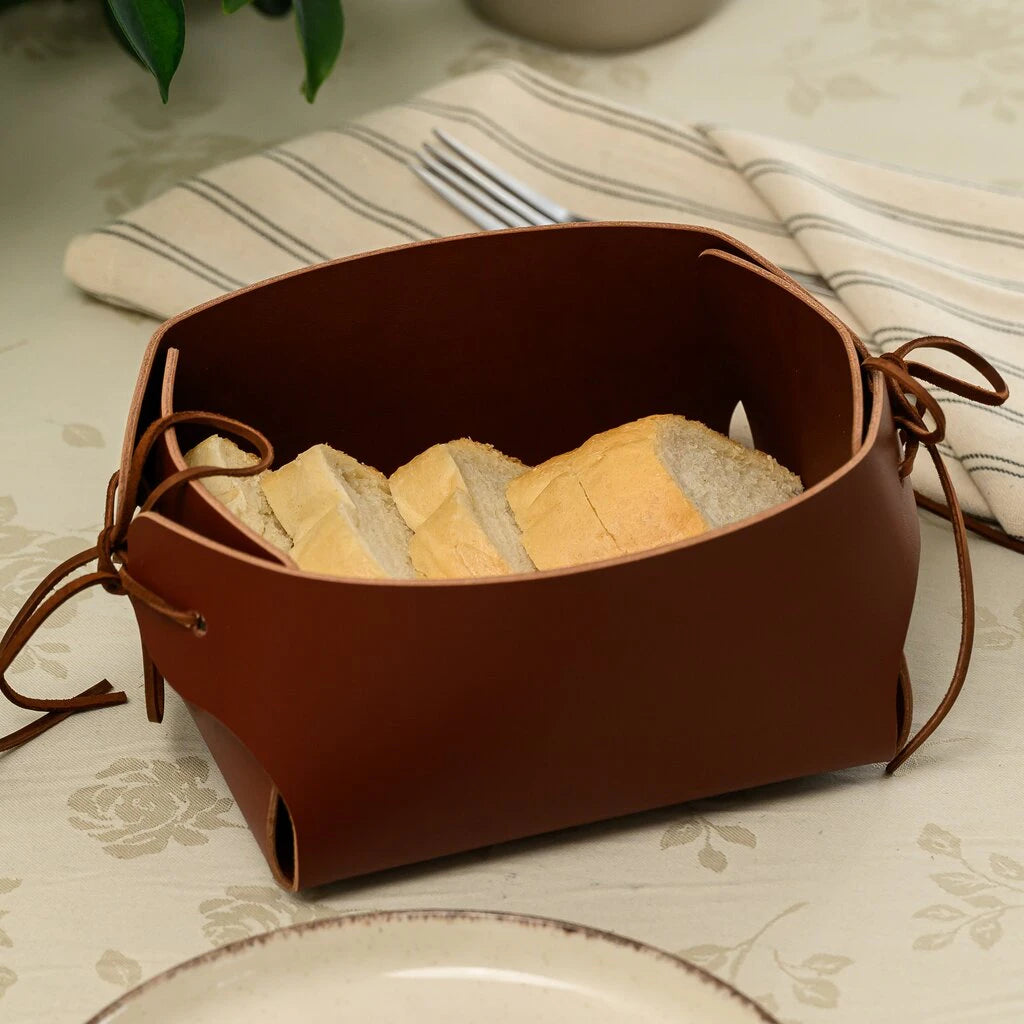 Rich brown leather bread holder with artisanal white bread, featuring unique folded design and leather string closures