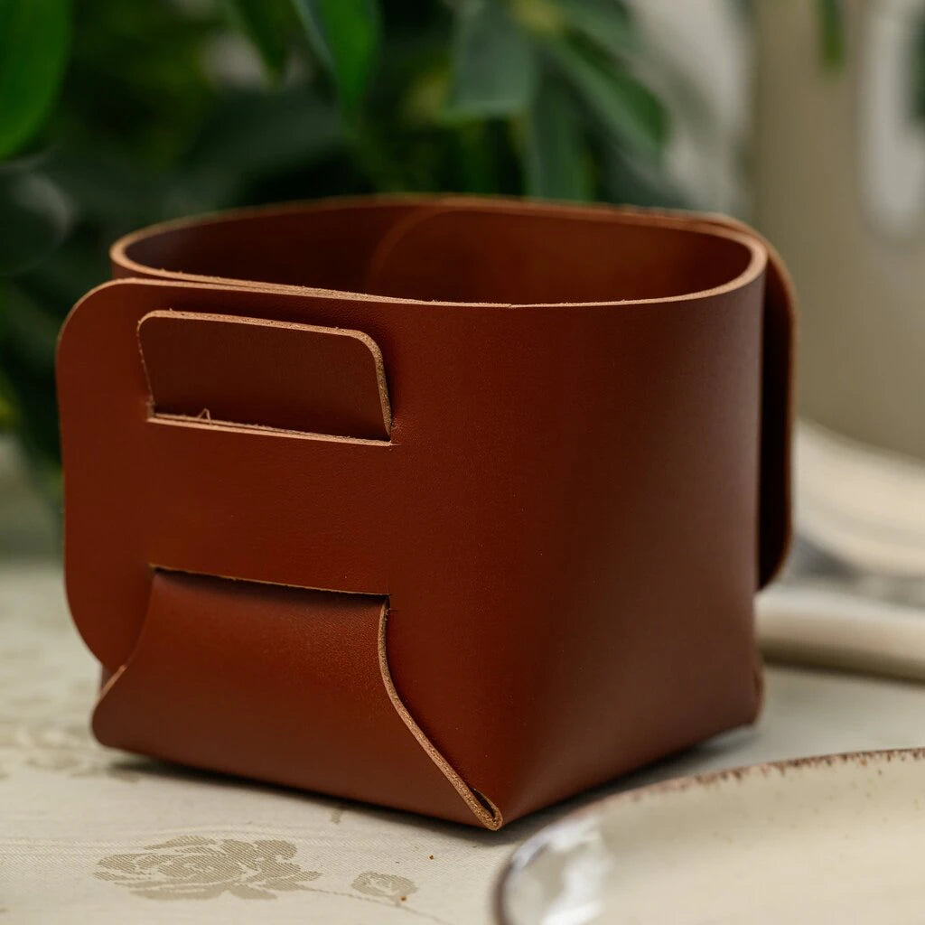 Empty square leather bread basket with slot-and-tab construction on a dining table