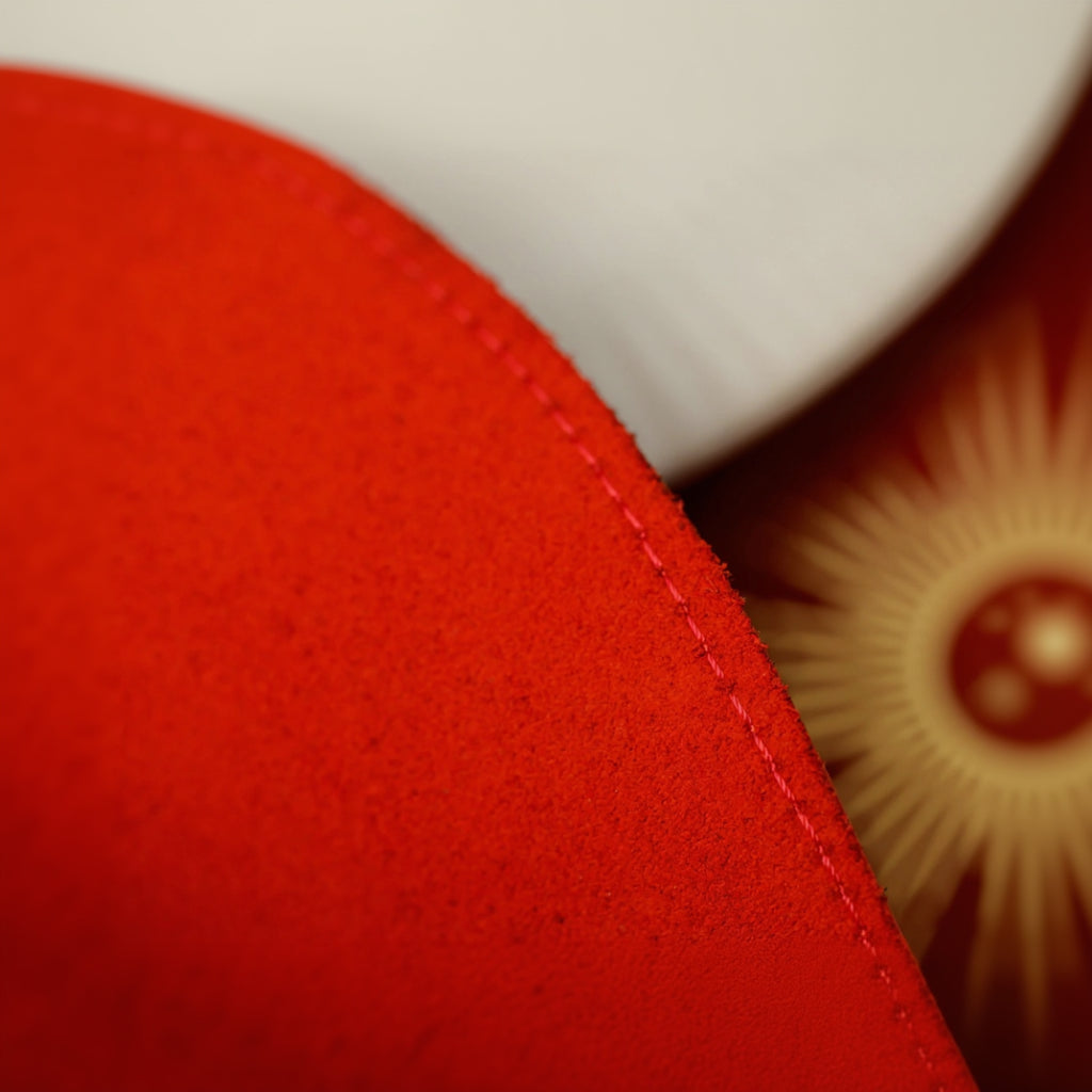 Detailed view of the underside of a red oval faux leather table mat, highlighting the high-quality suede-like lining designed for table surface protection and non-slip functionality