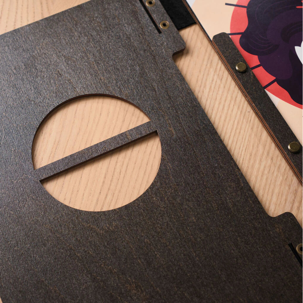 A close-up of the front cover's circular cutout with a horizontal wooden bar, resting on a light wood tabletop