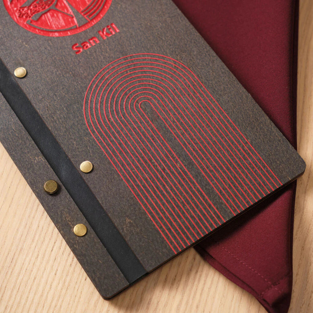 A high-angle detail shot of the red arched engraving, showing how the vibrant color pops against the dark, wenge-stained wooden cover.