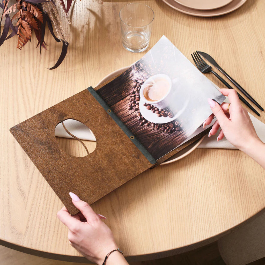 Side view of a dark walnut wood menu folder showing the white leather spine and polished rivets.