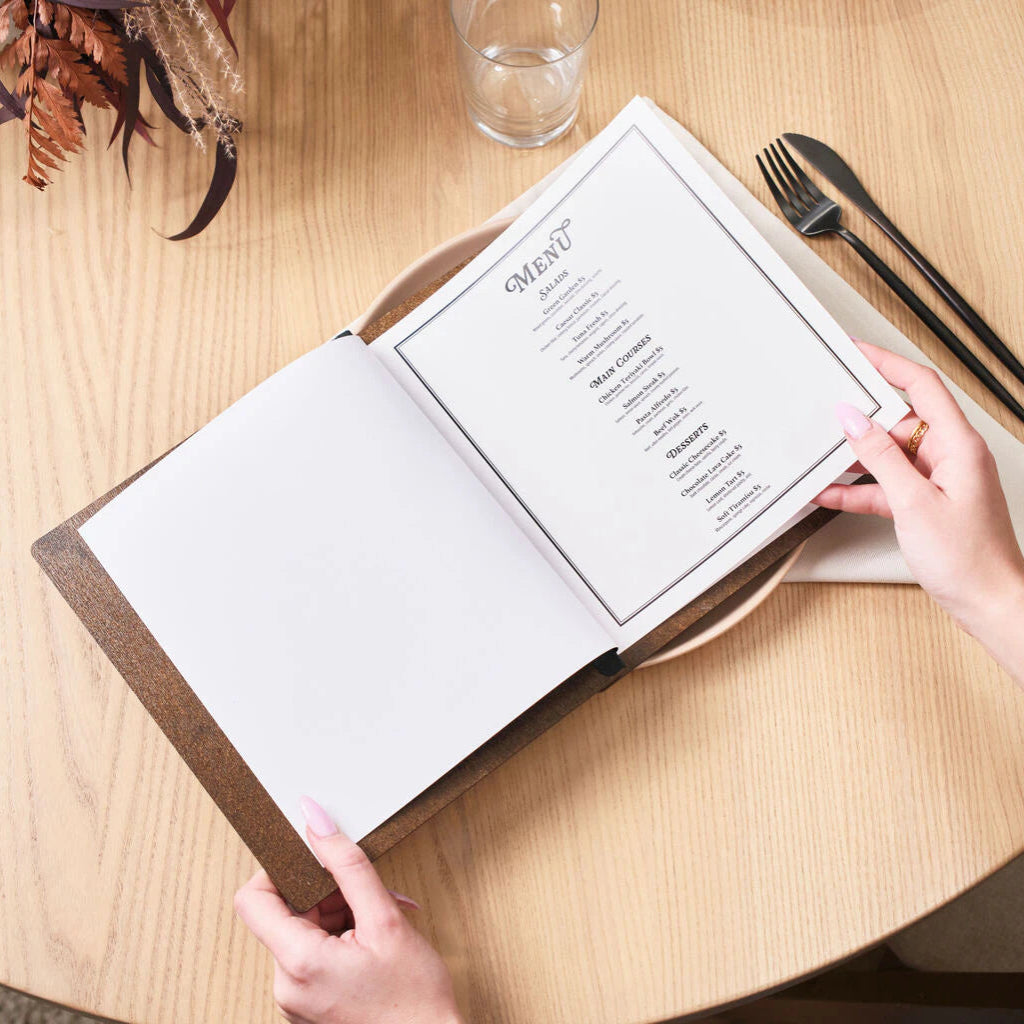 Open walnut wood menu showing a professional photo of a coffee drink alongside an engraved cover with a coffee bean cutout.