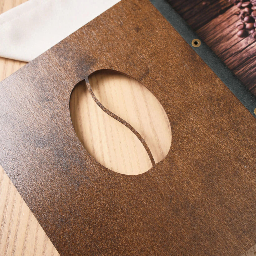 Detailed view of the handcrafted white leather and brass binding on a dark walnut wood restaurant menu.