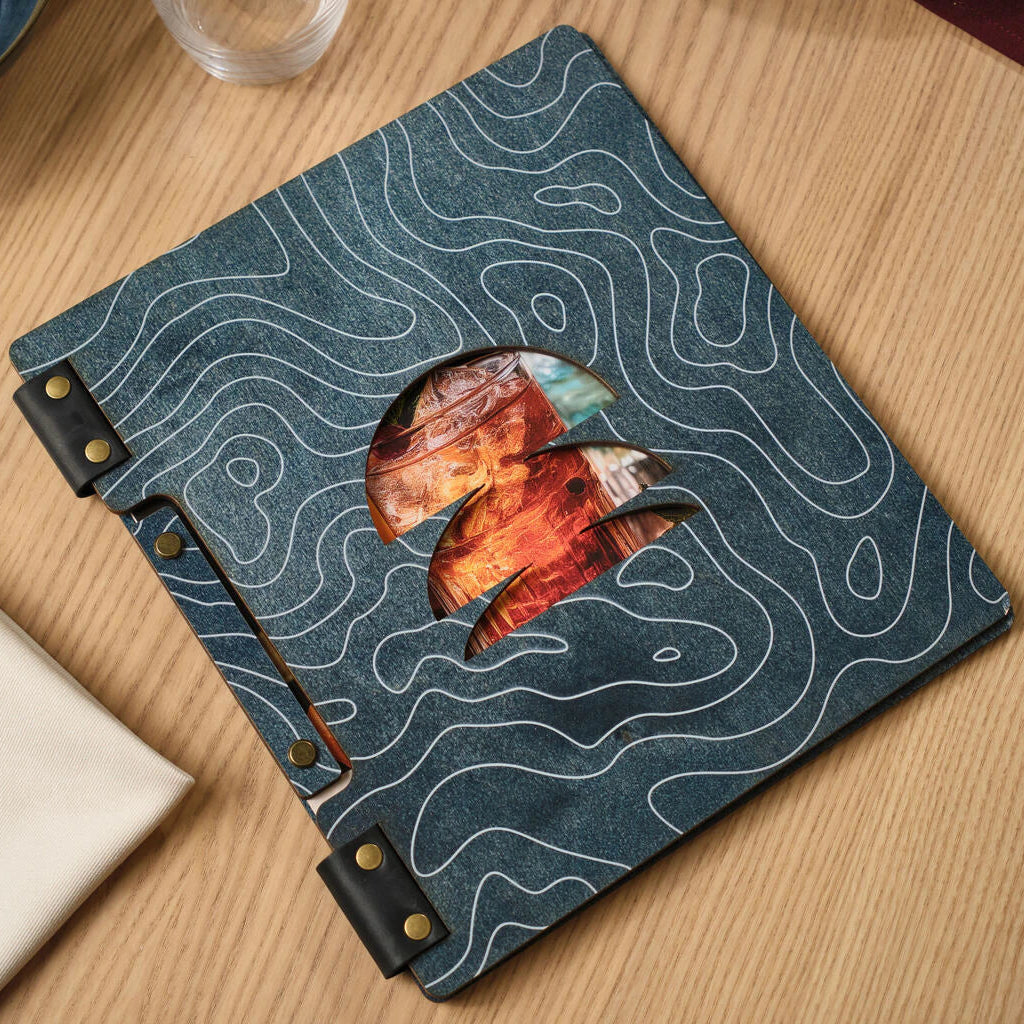 Front view of a blue wooden menu cover featuring a white topographic line pattern, black leather hinges with brass rivets, and a decorative window cutout