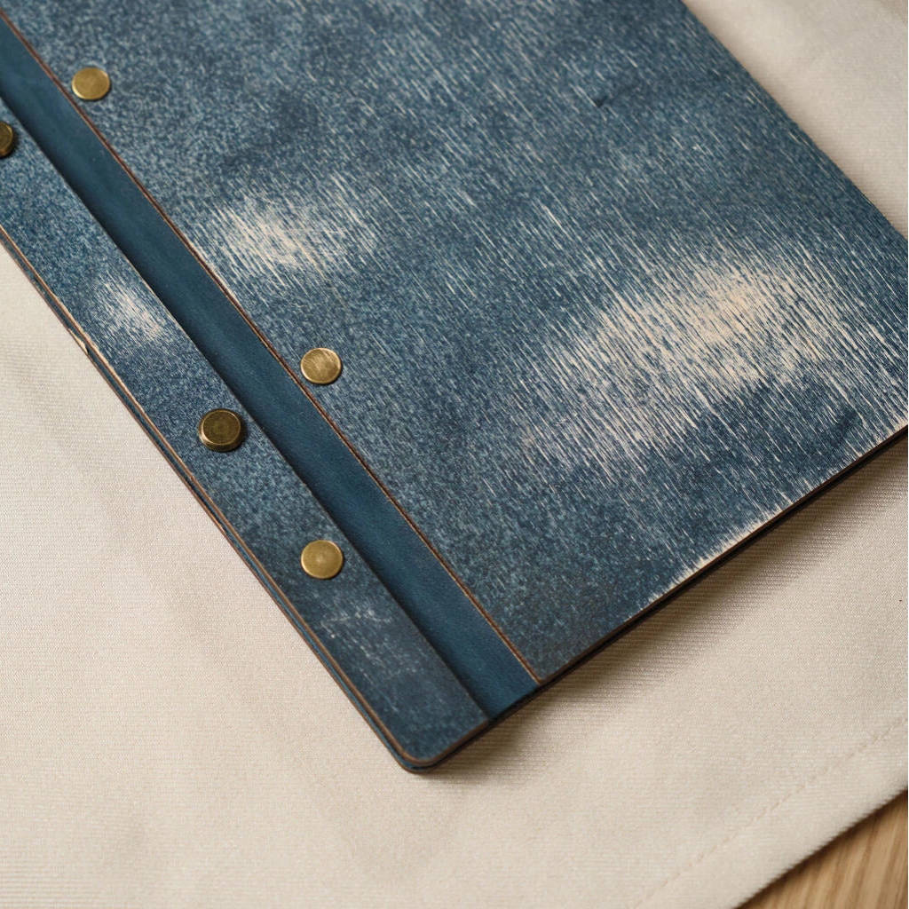 Close-up of the distressed blue wood texture and brass hardware on a premium restaurant menu