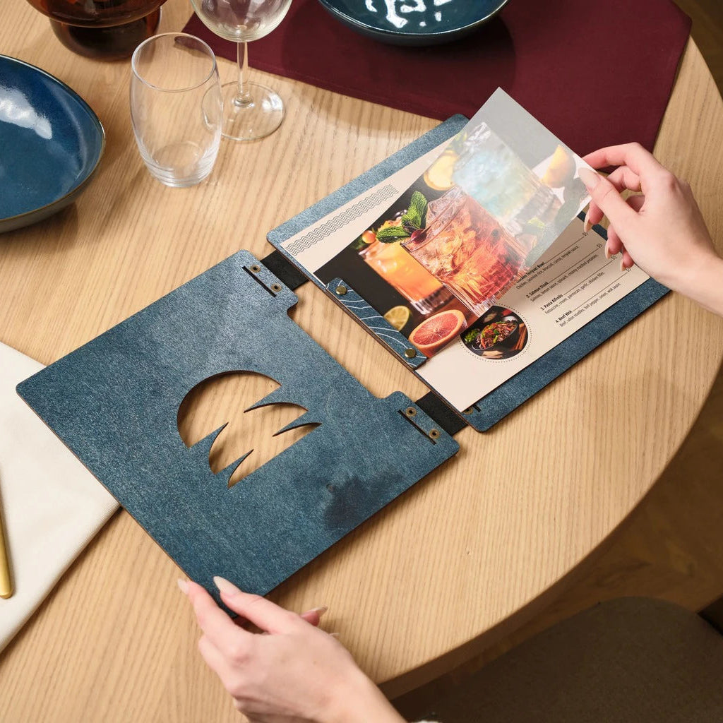 Modern open-style menu board with a blue textured finish, featuring a secure page-fastening system and a unique geometric window design