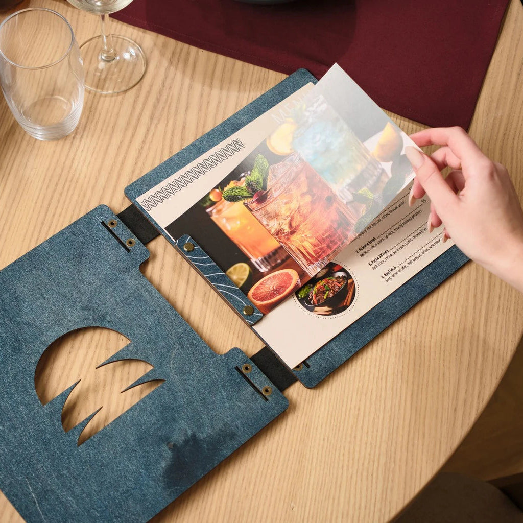Detail shot of an open restaurant menu folder highlighting the industrial-style brass screws and durable leather binding mechanism.