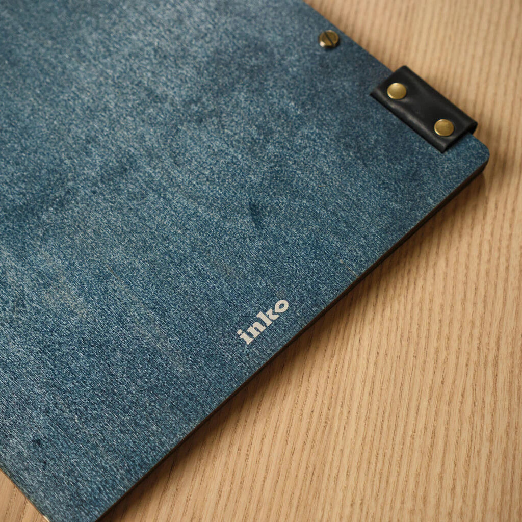 Macro detail of the brass screw fasteners on a blue textured menu cover, designed for easy page replacement and durability.