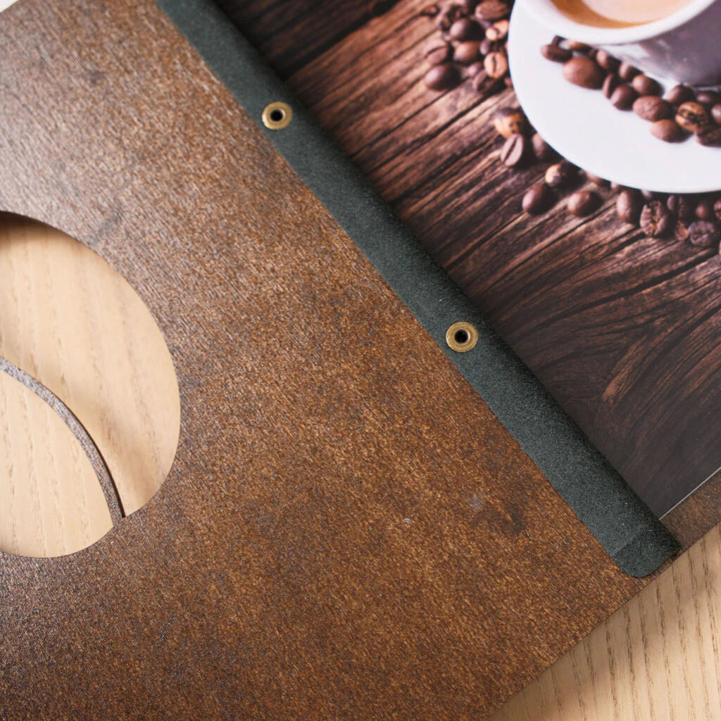 Macro shot of the deep walnut wood grain and precision-engraved wave lines on a dark menu cover.