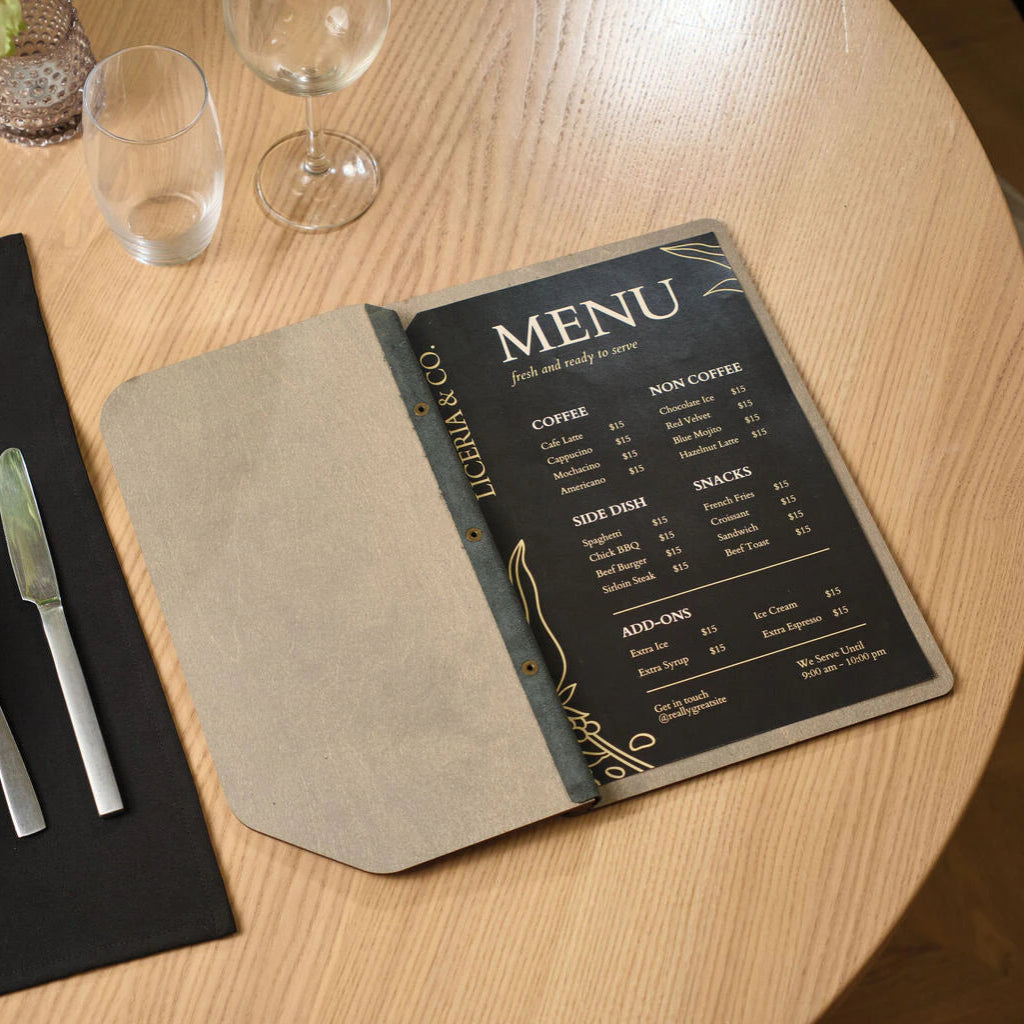 Interior view of an open wooden menu folder on a restaurant table, displaying a black printed menu for "Liceria & Co." with categories for coffee, snacks, and side dishes